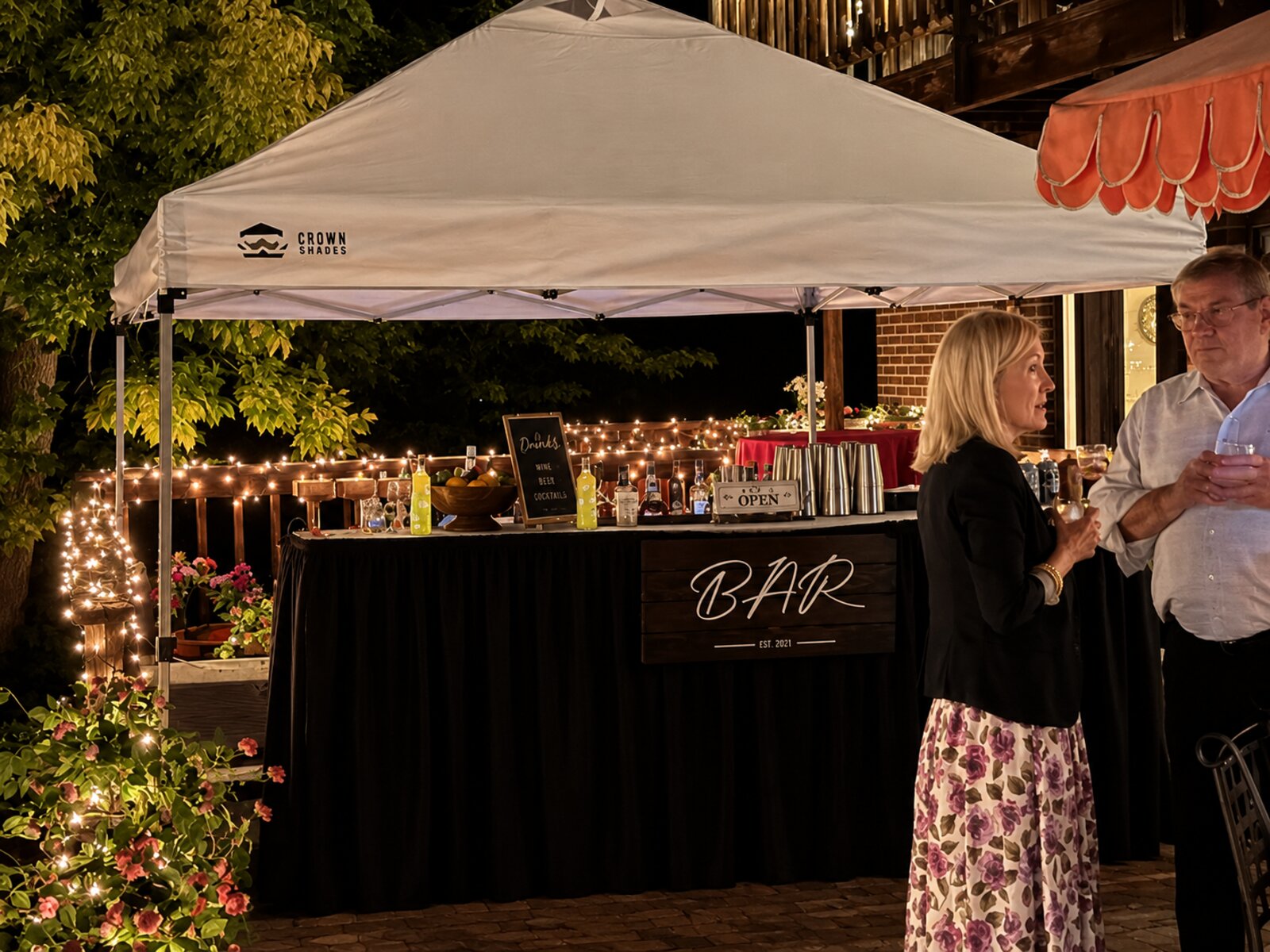Fully styled mobile bar setup under a lighted tent at dusk, with custom BAR sign