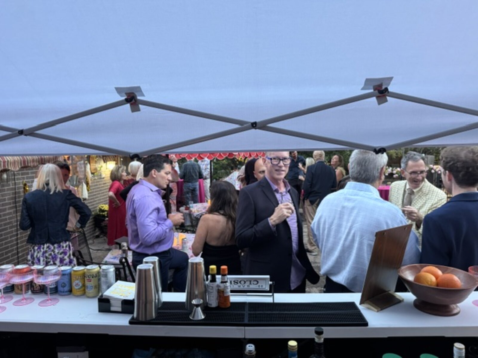 Bartender serving guests under the tent at an evening event